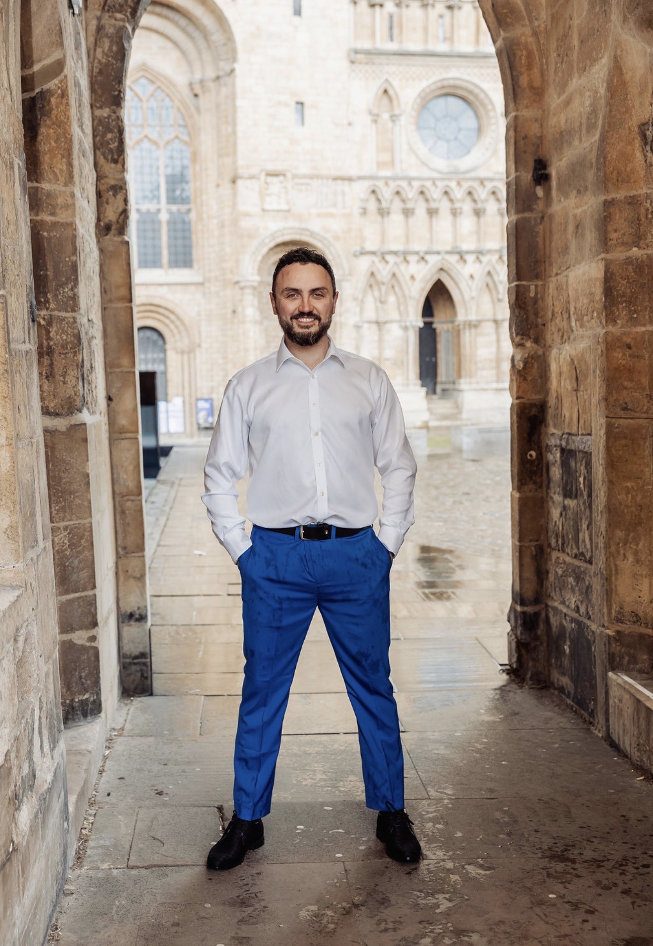 Elliott James Hunt in a white shirt and blue trousers beneath the stone archway. Photograph: Thomasxphotography